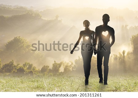 Lighting love, Silhouette of Asian couple hold hands walking on grassland.