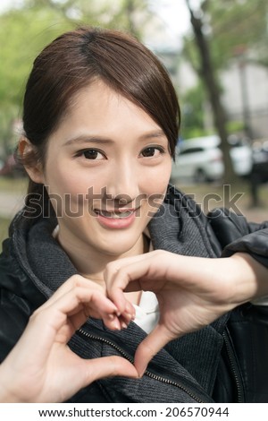 Asian young woman give you a gesture heart shape, close up portrait.