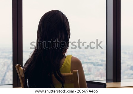 Asian woman sit on chair facing the window and using laptop at vacation.