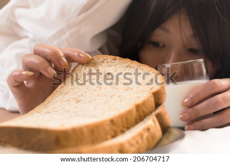 Woman\'s hand reaching from under duvet for breakfast in hotel.