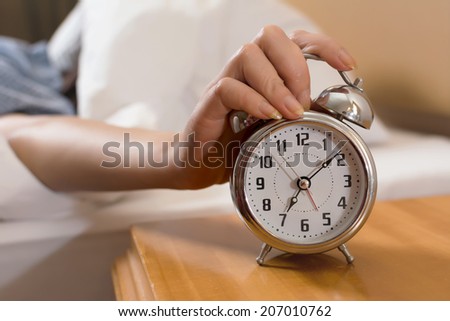 Closeup on female hand reaching to turn off alarm clock.