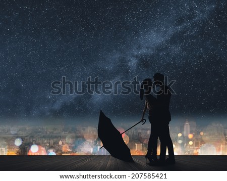 Silhouette of couple hug under stars.