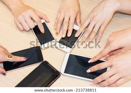 Woman using cellphones on desk.