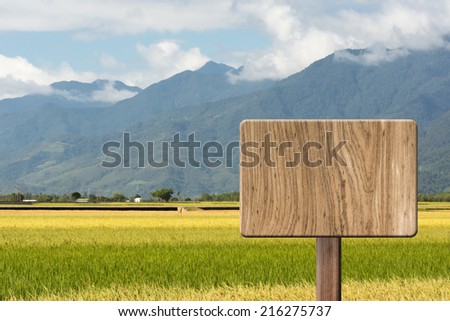 Blank wooden sign on field of paddy farm. Concept of rural, idyllic, tranquility etc.