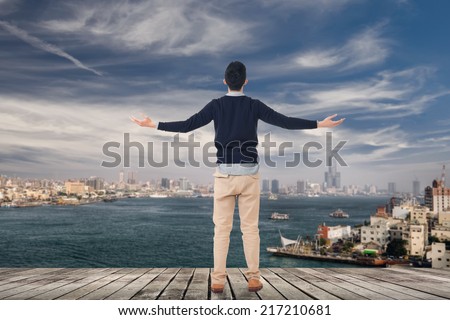 Asian man open arms and looking the skyline of the city, Kaohsiung, Taiwan, Asia.