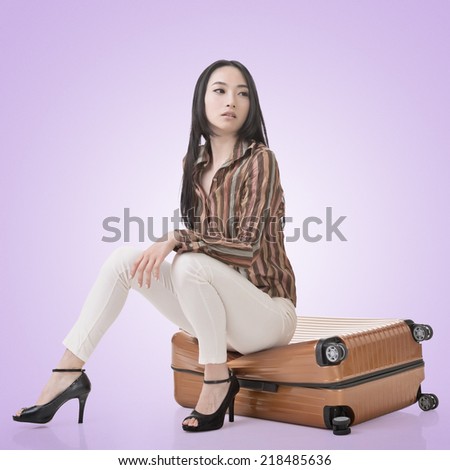 Asian woman thinking and sitting on a luggage.