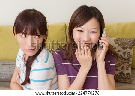 Concept of relationship, one girl talk on phone and another feel unhappy.