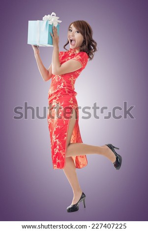 Smiling Chinese woman dress traditional cheongsam standing and holding a gift box at New Year, full length portrait  isolated.