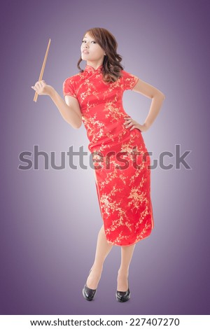 Smiling Chinese woman dress traditional cheongsam standing and holding chopsticks at New Year, full length portrait  isolated.