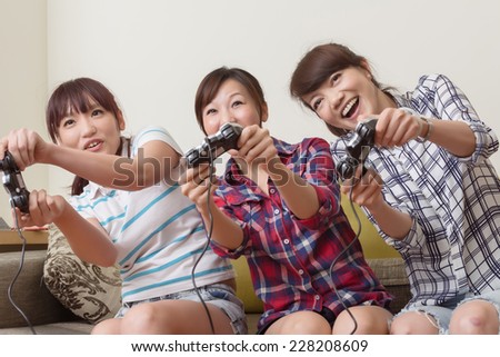 Friendship, technology, games and home concept - smiling female friends playing video games at home.