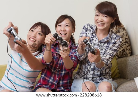 Friendship, technology, games and home concept - smiling female friends playing video games at home.