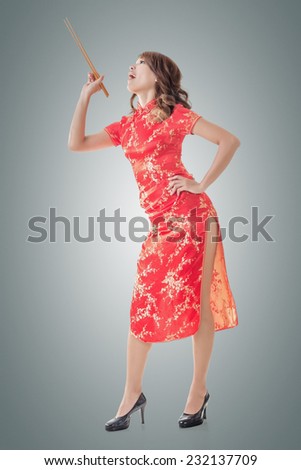 Smiling Chinese woman dress traditional cheongsam standing and holding chopsticks at New Year, full length portrait  isolated.