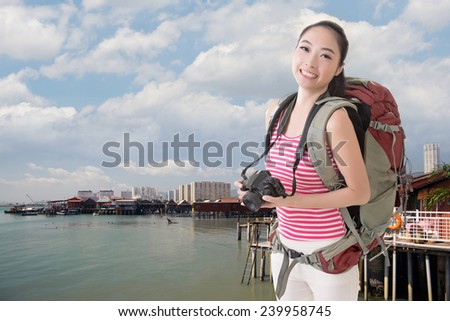 Happy smiling Asian young female backpacker with camera in Penang, Malaysia.