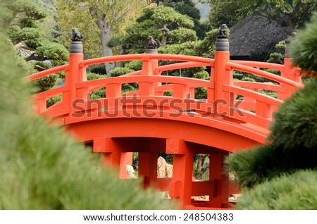 Traditional bridge of China in red color in green garden in Hong Kong, China, Asia.