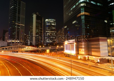 Colorful city night scene with modern skyscrapers and cars motion blurred in Hong Kong, Asia.