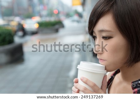 Asian girl holding cup of coffee at street in raining day in Taipei, Taiwan.