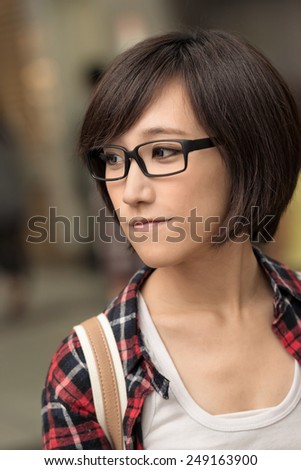 Closeup portrait of young Asian woman looking with peace and blue stand in outdoor street.