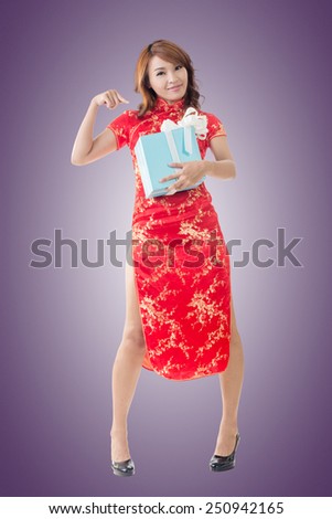 Smiling Chinese woman dress traditional cheongsam standing and holding a gift box at New Year, full length portrait isolated.