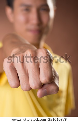 Fist hand sign of young guy of Chinese, closeup portrait in studio.