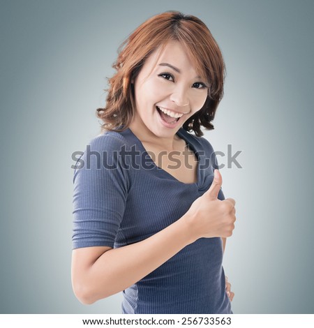 Smiling Asian woman give you a thumb up gesture.