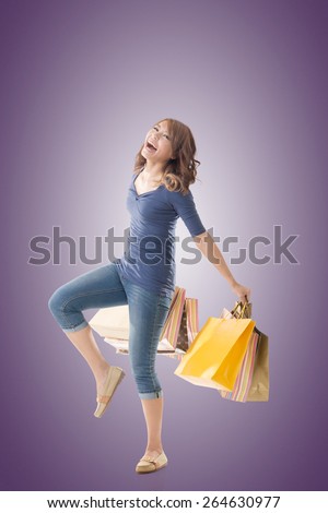 Cheerful shopping woman of Asian holding bags, full length portrait isolated.