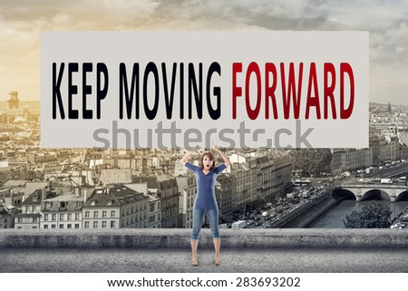 Keep moving forward, words on blank board hold by a young girl in the outdoor.