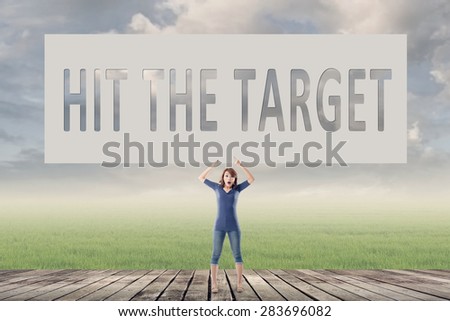 Hit the target, words on blank board hold by a young girl in the outdoor.