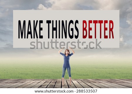 Make things better, words on blank board hold by a young girl in the outdoor.