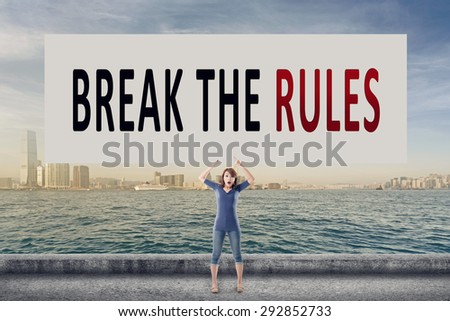 Break the rules, words on blank board hold by a young girl in the outdoor.