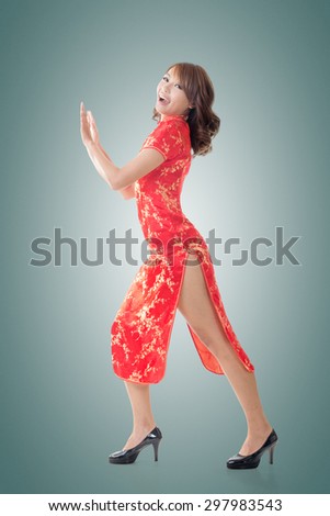 Chinese woman dress traditional cheongsam and push something at New Year, full length portrait isolated.