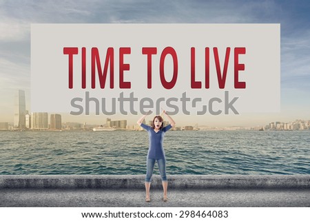 Time to live, words on blank board hold by a young girl in the outdoor.