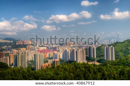 Tall apartments with green mountain under blue sky in Hong Kong.