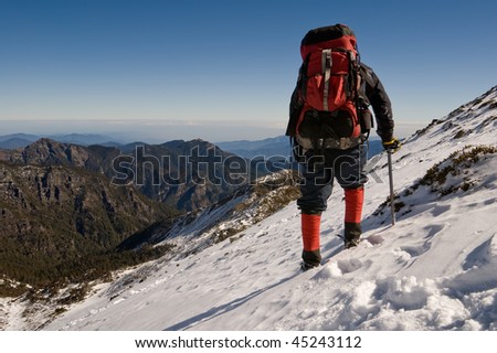 Man with backpack walk on ice snow slap on winter mountain.