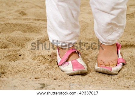 Children take off her shoes on sand prepare to play.