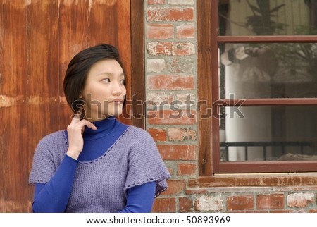 Woman portrait of watch and think in front of old door and window.