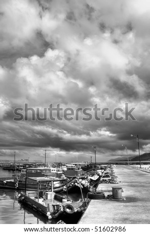 Dramatic landscape of storm scenic in harbor with boats on dock.