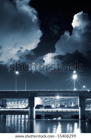City night scene of bridge with dramtic clouds in sky.
