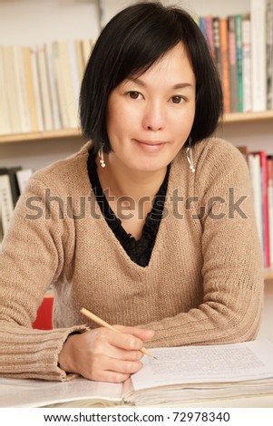 Asian woman working at home with smiling expression on face.
