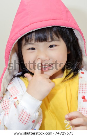 Adorable Asian girl pick her nose, closeup portrait of funny expression on face.