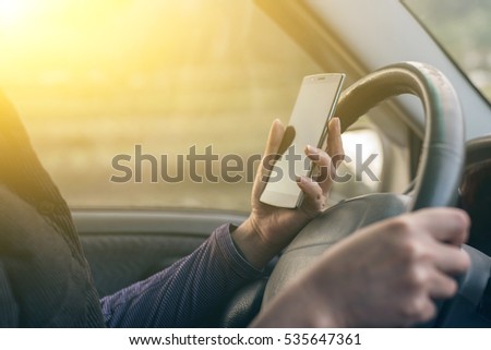 women driver with a cell phone in hand while driving