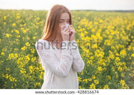 Pollen allergy, girl sneezing in a field of flowers.