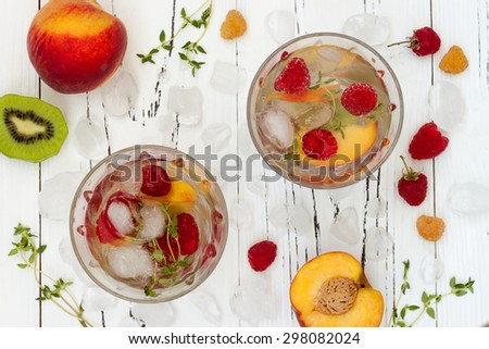 Healthy detox fruit infused flavored water. Top view. Summer refreshing homemade cocktail with fruits and thyme on white wooden table