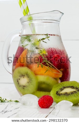 Healthy detox fruit infused flavored water. Summer refreshing homemade cocktail with fruits and thyme on white wooden table