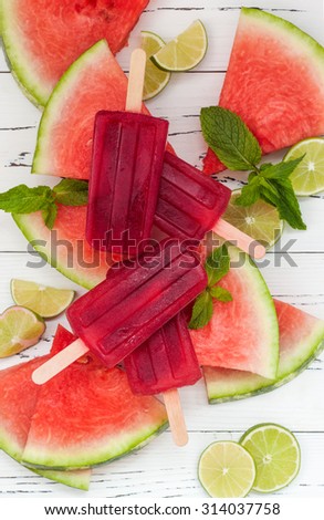 Watermelon mojito alcohol popsicles - poptails - ice pops, served on watermelon slices with lime and mint leaves. Top view. Cinco de Mayo agua fresca popsicles - party recipe