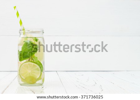 Refreshing homemade lime and mint cocktail over old vintage wooden table. Detox fruit infused flavored water. Clean eating. Copy space background