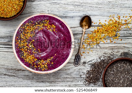 Acai breakfast superfoods smoothies bowl with chia seeds, bee pollen toppings. Immune boosting, anti inflammatory smoothie with turmeric, honey, maca powder. Overhead, top view, flat lay, copy space.