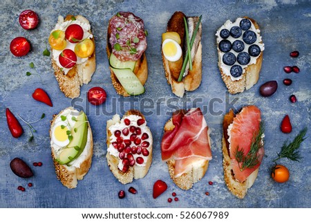 Brushetta or authentic traditional spanish tapas set for lunch table. Sharing antipasti on party or summer picnic time over blue rustic background. Top view, flat lay.