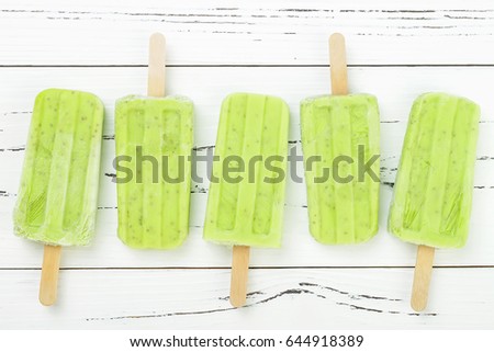 Homemade vegan green tea matcha mint coconut milk popsicles - ice pops - paletas with chia seeds on rustic white wooden background