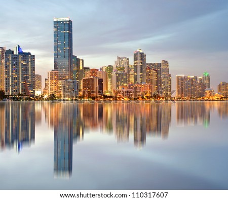 Miami Florida illuminated downtown buildings at sunset with reflections in the water of Biscayne Bay. Panoramic skyline of the World famous travel location