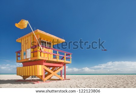 Miami Beach Florida, Lifeguard House In A Typical Colorful Art Deco Style On A Bright Sunny Summer Day, With Blue Sky And Atlantic Ocean In The Background. World Famous Travel Location.